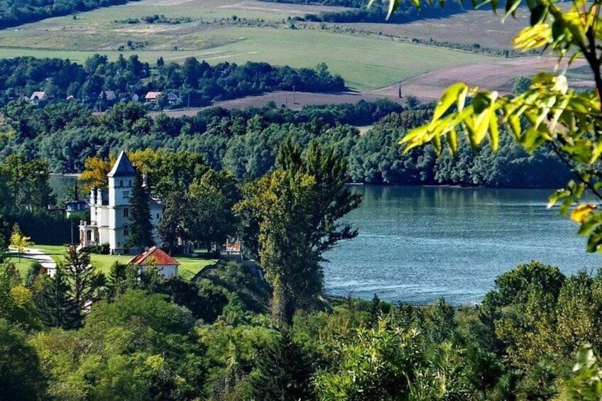 A lake surrounded by trees and a white building with a red roof. 1