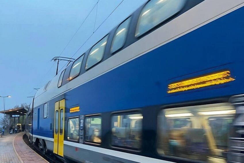 A blue train with yellow doors and windows, moving along the tracks. 3