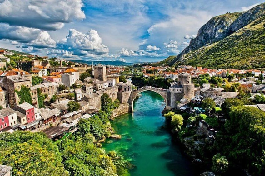 A historic town with a river, a bridge, and a mountain backdrop. 5