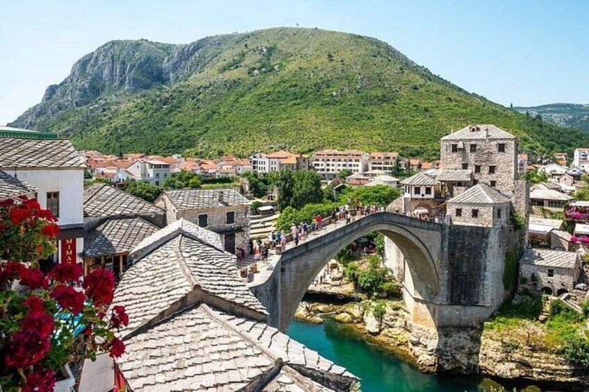 A stone bridge over a river, historic buildings, and a mountainous backdrop. 4