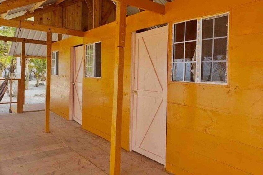 A wooden building with a corrugated metal roof, large windows, and a door. 3
