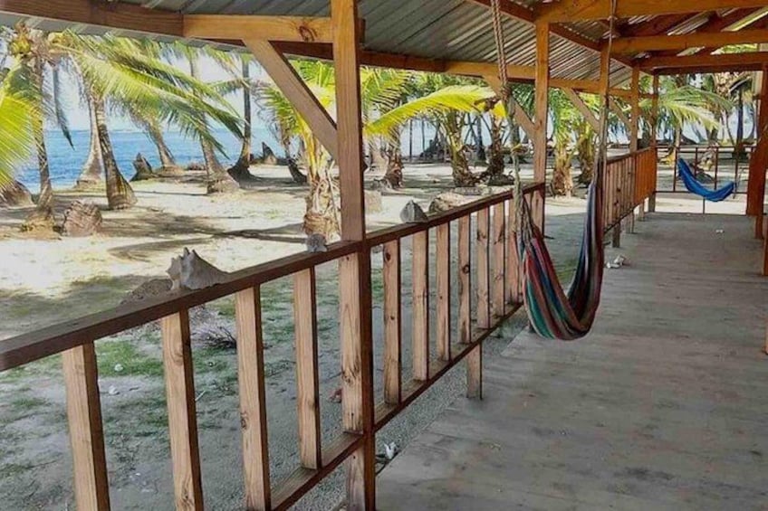 A beach with a wooden structure, palm trees, and a hammock. 2