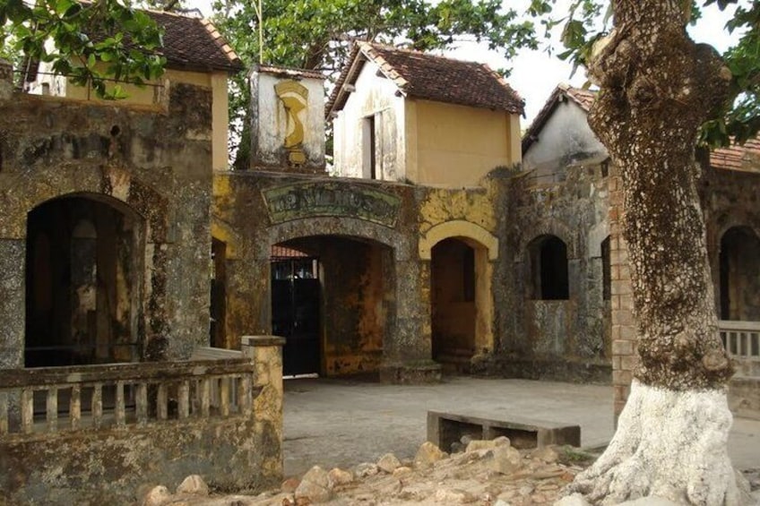 An old courtyard with stone walls, a tree, and a building with a tiled roof. 2