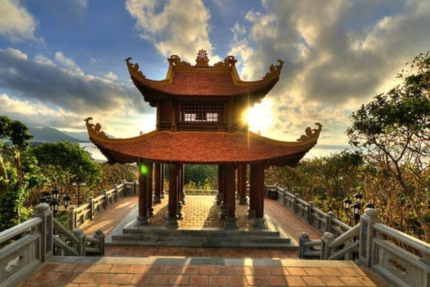 A traditional Chinese pavilion with a tiled roof, surrounded by a stone pathway and railings. 2