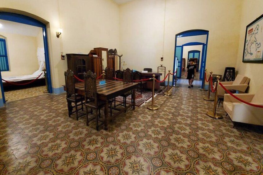 A room with a patterned carpet, a wooden table with chairs, and a red rope barrier. 5