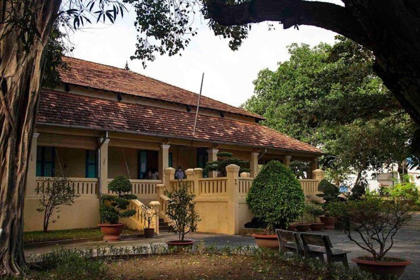 A traditional building with a tiled roof, surrounded by potted plants and a bench. 1