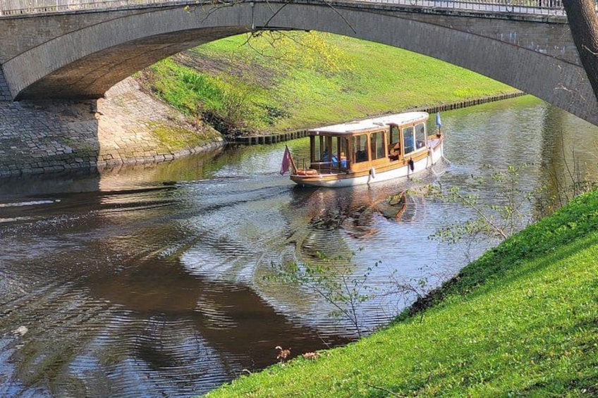 A river with a boat, a bridge, and grassy banks. 2