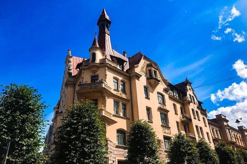 A historic building with ornate architecture, a prominent tower, and lush green trees in the foreground. 4