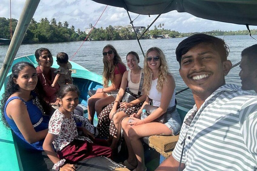 Een groep mensen op een boot, met water en groen in de achtergrond. 5