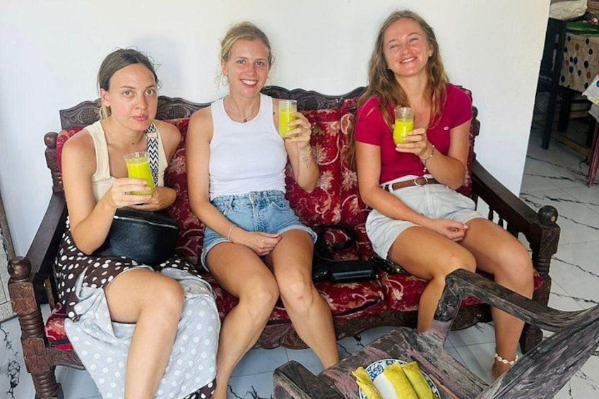 Drie personen zitten op een rode, gestreepte bank met drankjes. 4