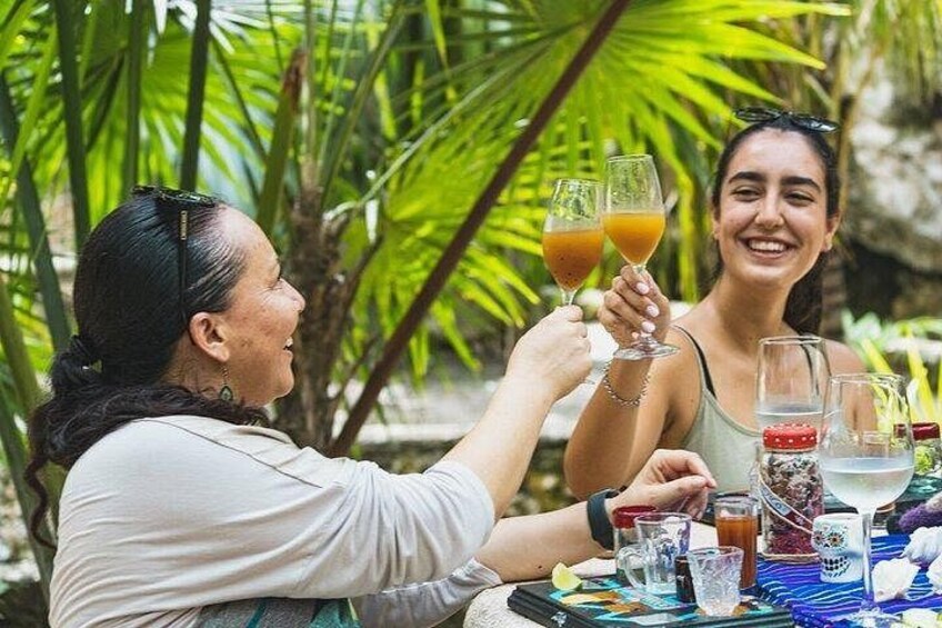 Dos personas brindando con bebidas en una mesa al aire libre, con diversas opciones y un entorno tropical. 2