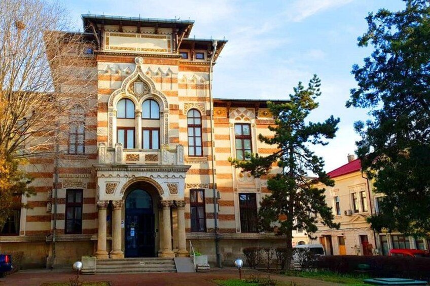 A historic building with ornate architecture, a large arched entrance, and a red roof. 3