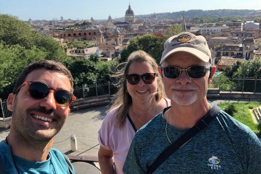 Tres personas en una plataforma de observación, con un paisaje urbano al fondo. 2