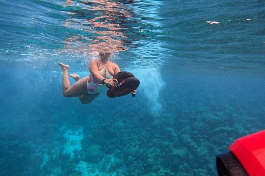 A person underwater in a pool, holding a camera. 3