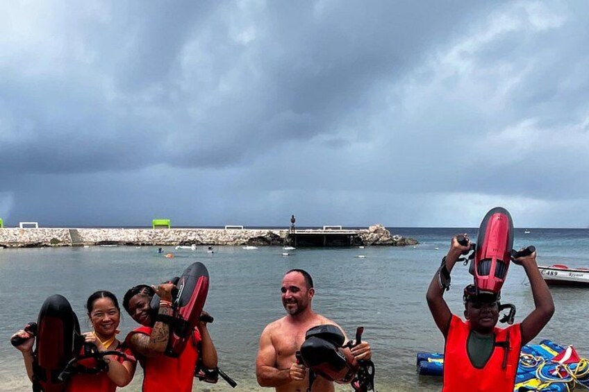 A group of people holding surfboards by a rocky pier with the ocean in the background. 5