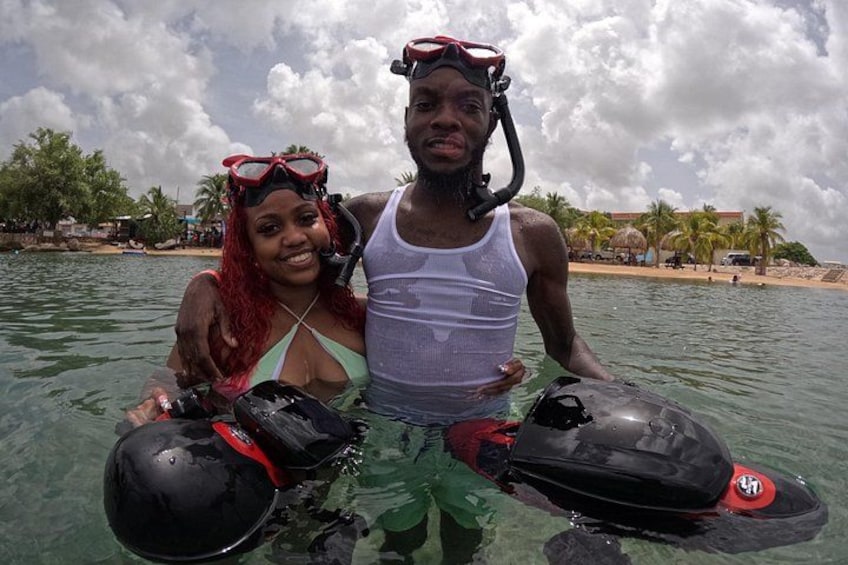 Two people on a jet ski, water, and a beach with palm trees. 5