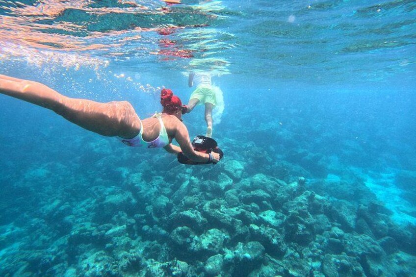 A person swimming underwater with a snorkel and fins, surrounded by coral reefs. 1