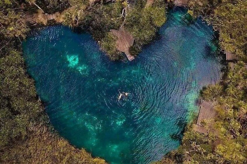 Un cuerpo de agua con forma de corazón rodeado de vegetación densa y pasarelas de madera. 4