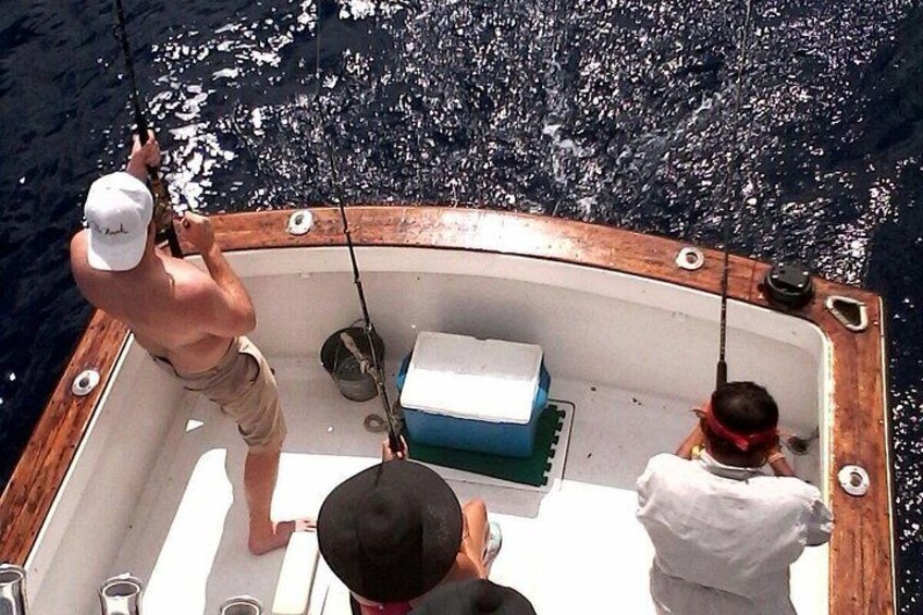 Un bote con dos personas pescando, un enfriador y una caña de pescar. 3