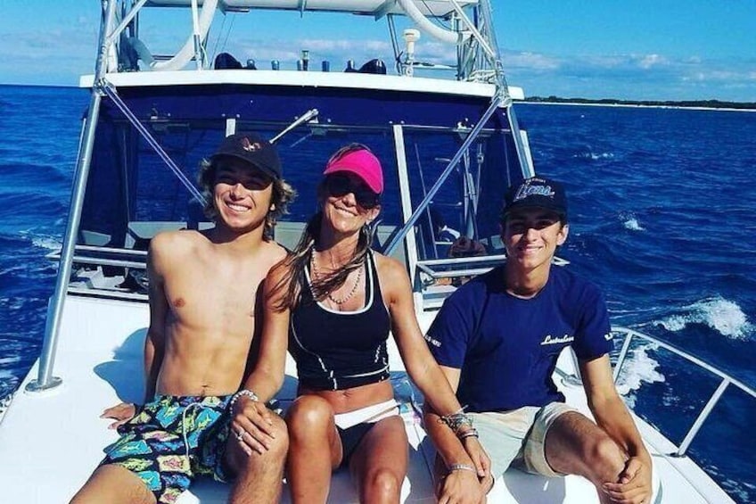 Tres personas en un bote con el océano y una costa lejana al fondo. 2