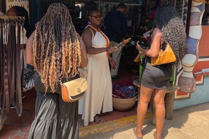Escena de mercado con gente comprando y una exhibición de telas coloridas. 4