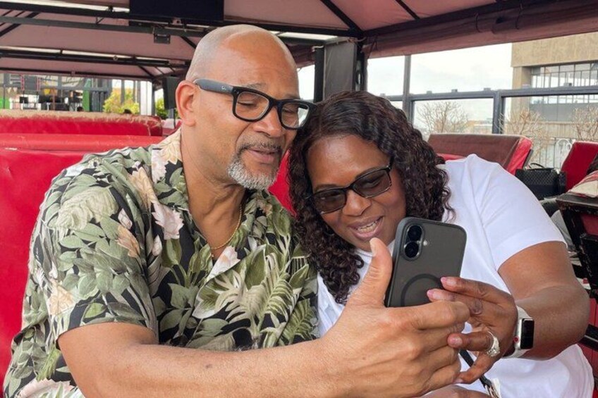 Two people sitting at an outdoor table, one holding a smartphone. 2