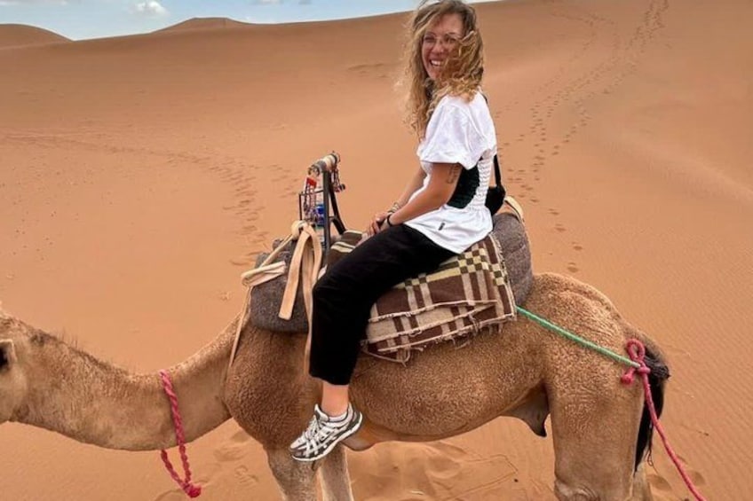 A person riding a camel in a desert with sand dunes in the background. 2