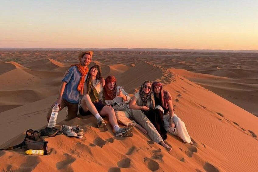 Un gruppo di persone sedute sulle dune di sabbia in un paesaggio desertico. 1