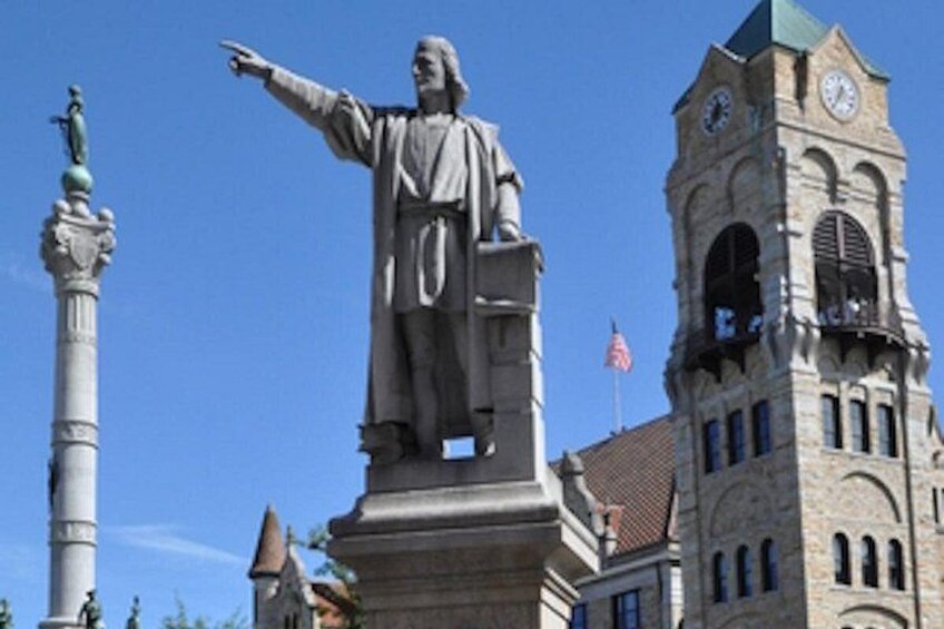 A statue of a historical figure, a clock tower, and a flag. 5