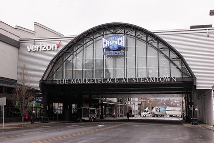 A modern shopping center entrance with a glass facade and a curved roof. 4