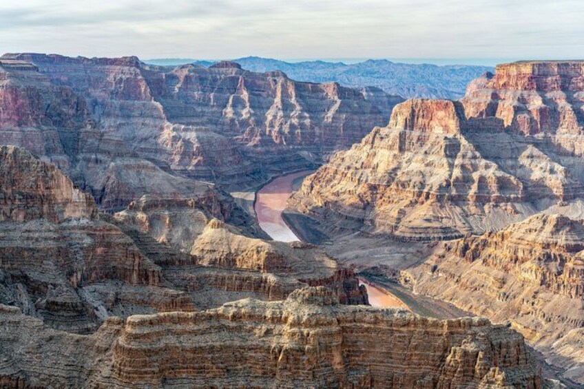 A canyon with layered rock formations and a river running through it. 4