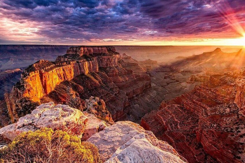 A canyon with layered rock formations and a sunset. 2