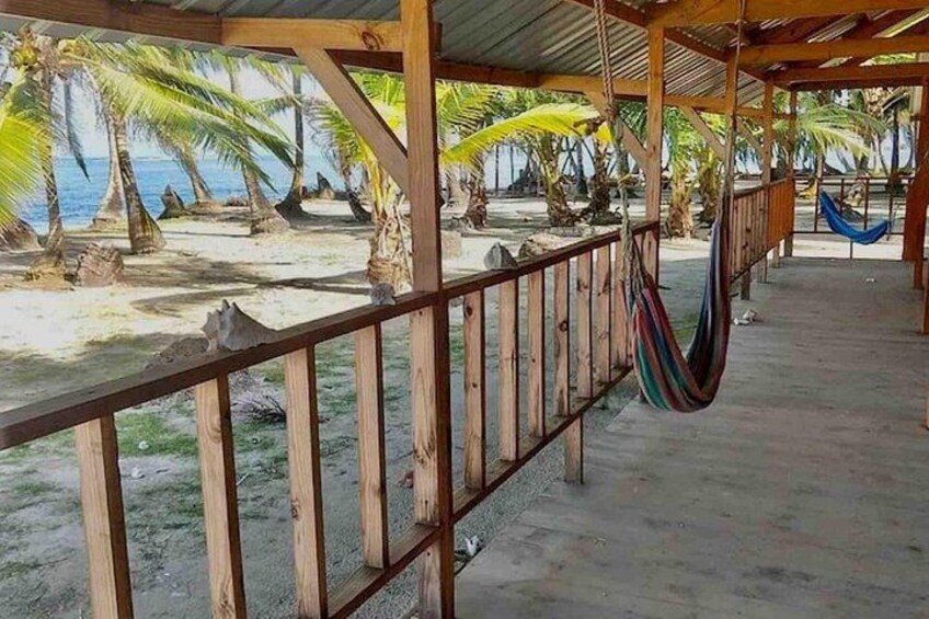 A beach with a wooden structure, palm trees, and a hammock. 3