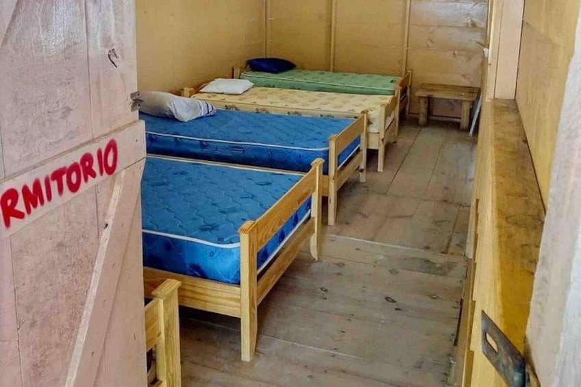A room with bunk beds and a wooden bench. 4