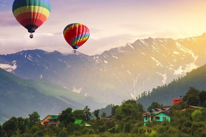 Deux montgolfières, une chaîne de montagnes et des maisons dans une vallée. 1