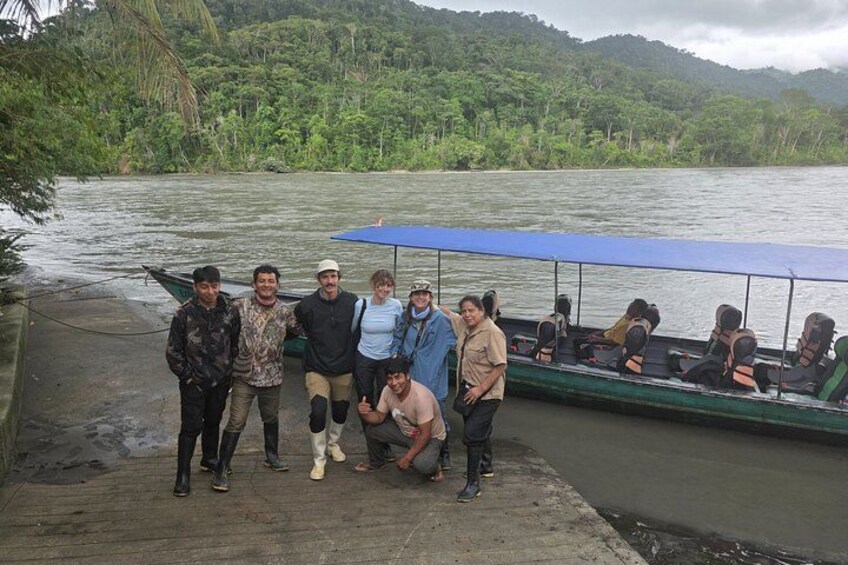 A group of people on a boat docked at a river with lush greenery in the background. 2