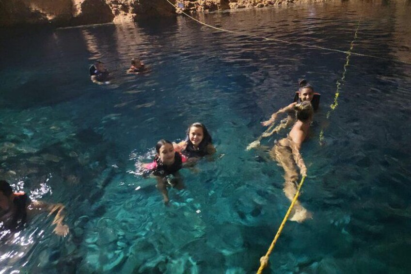 People swimming in a clear pool with ropes. 2