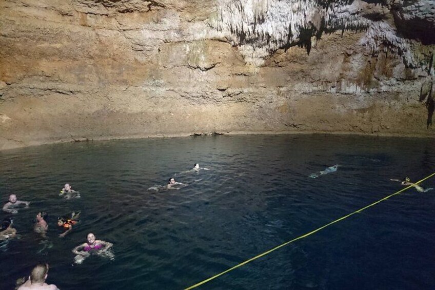 A group of people swimming in a natural pool with rocky walls. 3