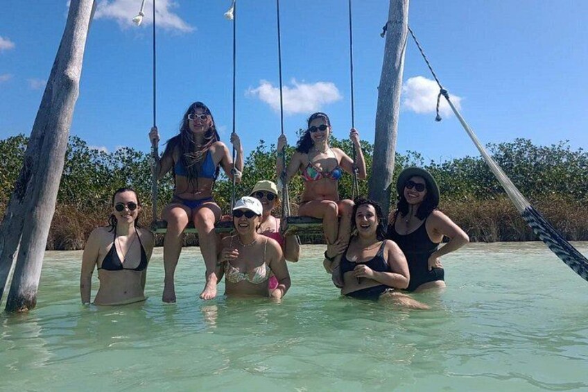 A group of people in a shallow water body with a swing set. 4