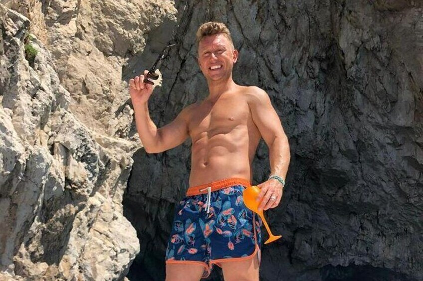 A person wearing swim trunks standing in front of a rocky cliff. 3