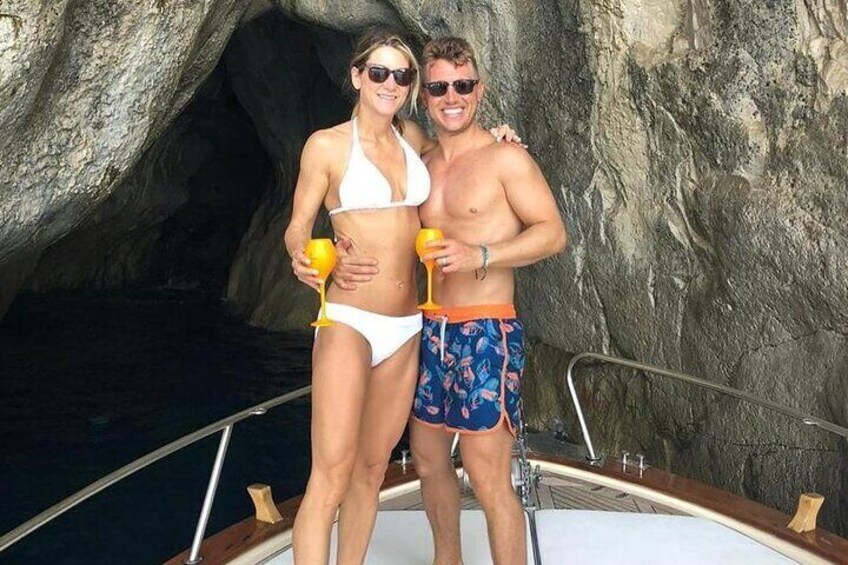 A couple on a boat near a rocky cave entrance. 4