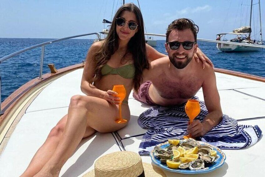 Two people on a boat with a plate of seafood and drinks. 2