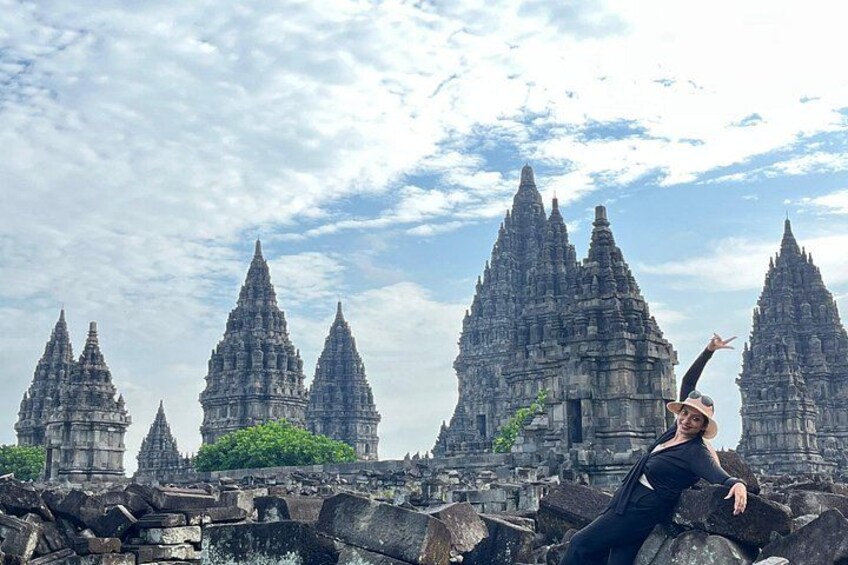A person in black attire posing in front of ancient stone structures with multiple pointed peaks. 2
