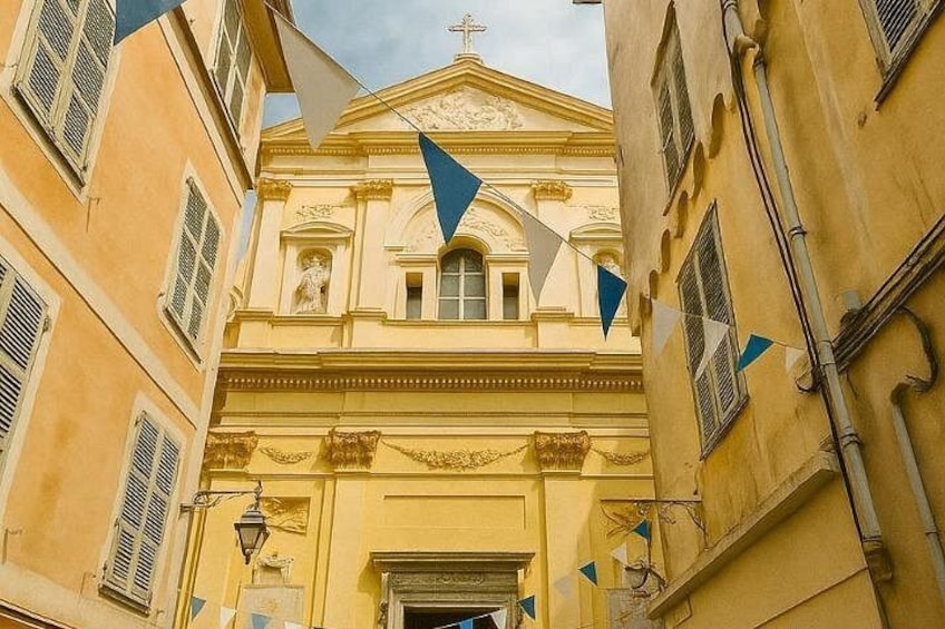 Un edificio amarillo con una cruz en la parte superior, banderas triangulares y un farol. 5