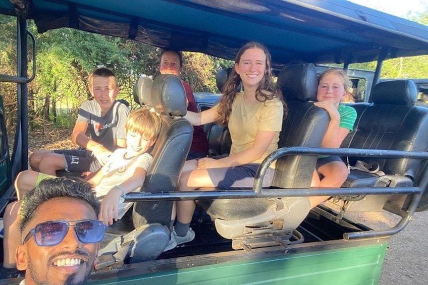 A group of people seated in a vehicle with a green exterior. 3