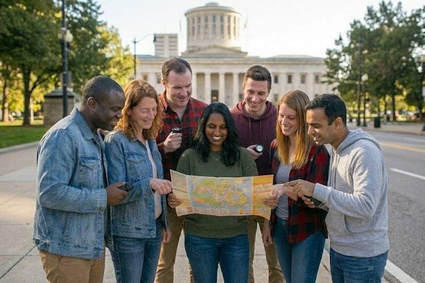 A group of people examining a map outdoors with a building in the background. 1