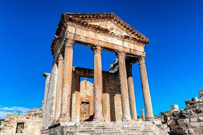 Ancient ruins with columns and a partially intact structure against a clear blue sky. 2