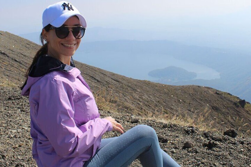 A person sitting on a rocky hillside with a mountainous landscape in the background. 1