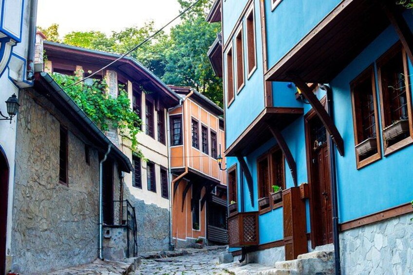 A narrow street with traditional buildings, stone walls, and wooden balconies. 5