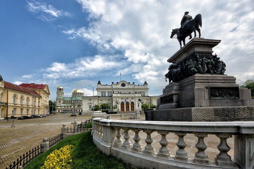 A statue of a mounted figure, a fountain, and classical architecture in an urban square. 3